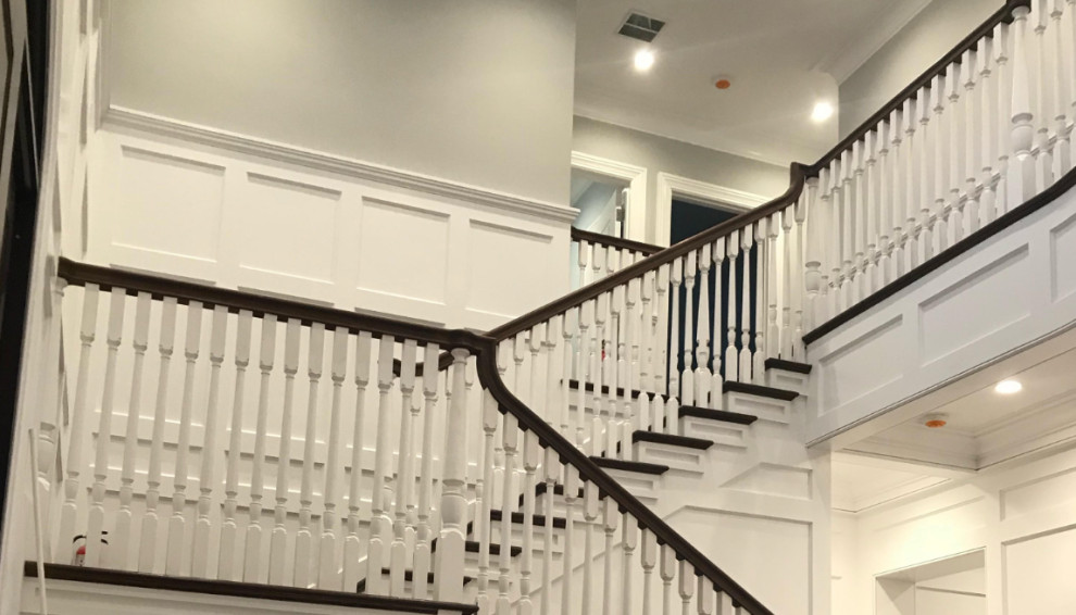 This is an example of a large classic wood u-shaped wood railing staircase in Boston with painted wood risers.