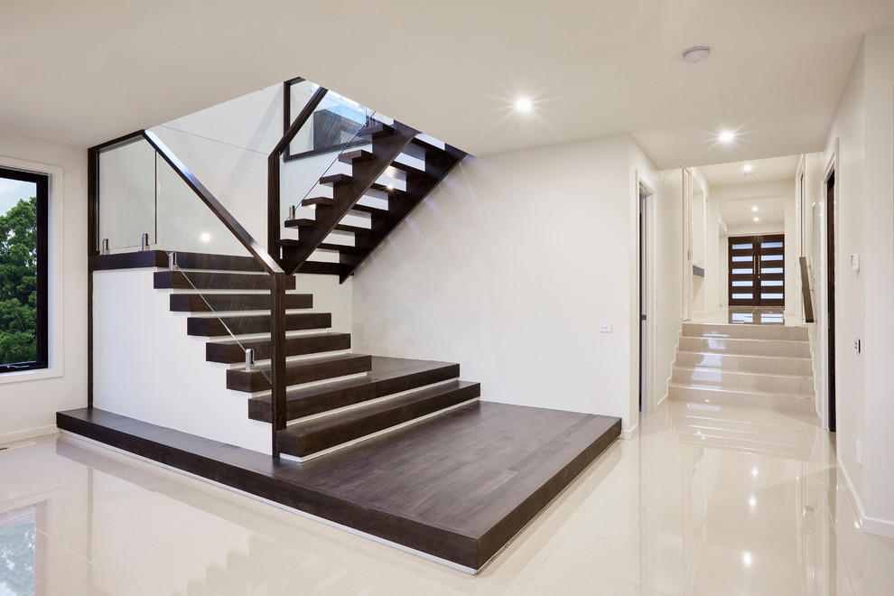 Idée de décoration pour un escalier design en U de taille moyenne avec des marches en bois, des contremarches en verre et un garde-corps en bois.