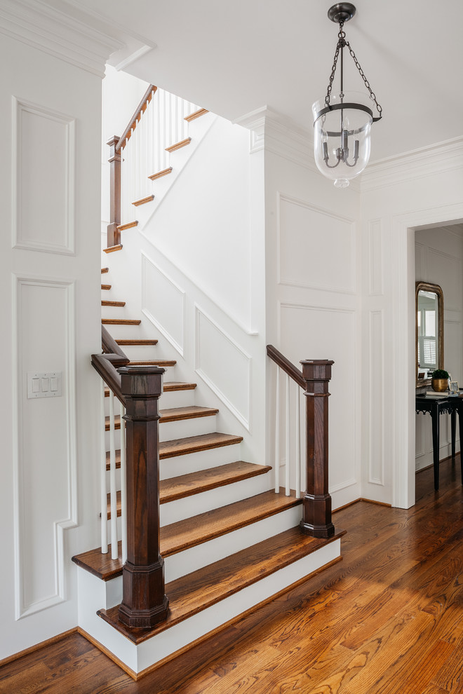 Ejemplo de escalera en U tradicional extra grande con escalones de madera, contrahuellas de madera pintada, barandilla de madera y panelado