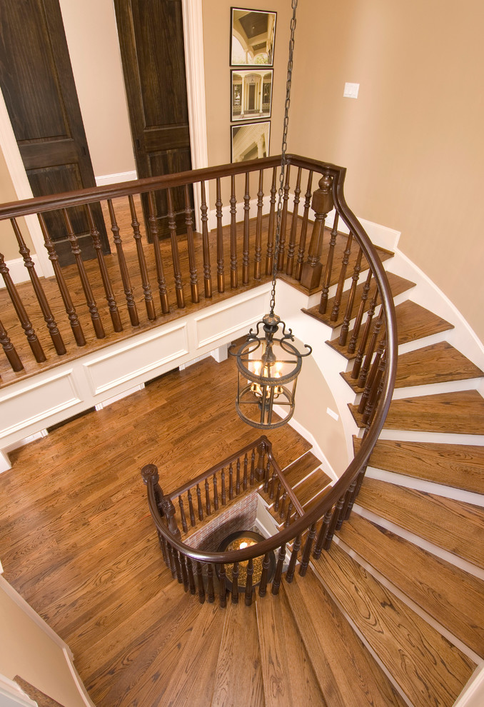 Источник вдохновения для домашнего уюта: огромная изогнутая лестница в классическом стиле с деревянными ступенями и деревянными перилами