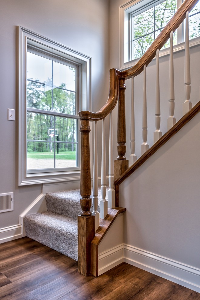 Photo of a small traditional carpeted l-shaped wood railing staircase in Other with carpeted risers.
