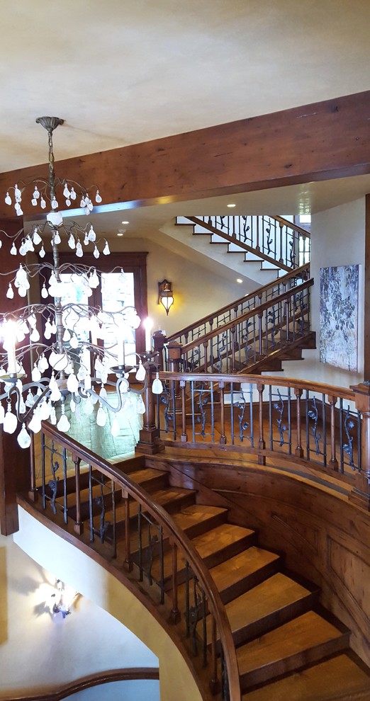 Idée de décoration pour un très grand escalier courbe chalet avec des marches en bois et des contremarches en bois.