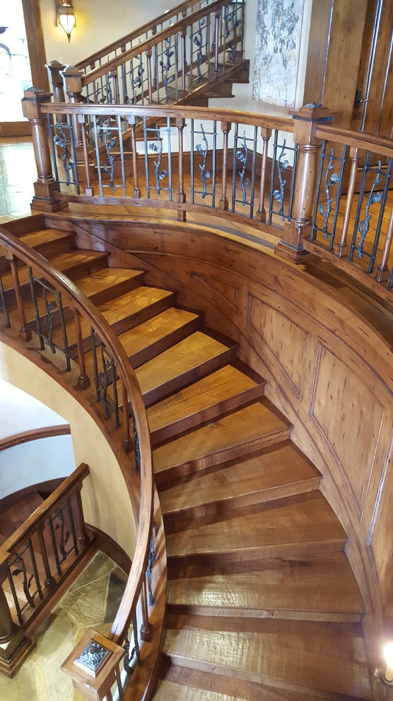 Example of a huge mountain style wooden curved staircase design in Salt Lake City with wooden risers