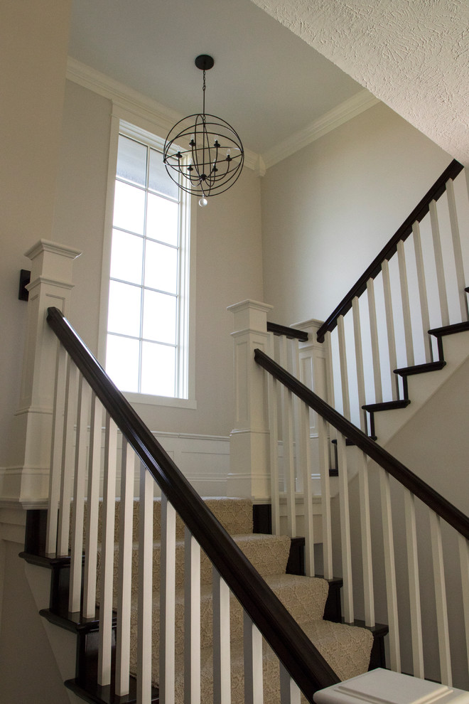 Large contemporary carpeted u-shaped wood railing staircase in Grand Rapids with carpeted risers.