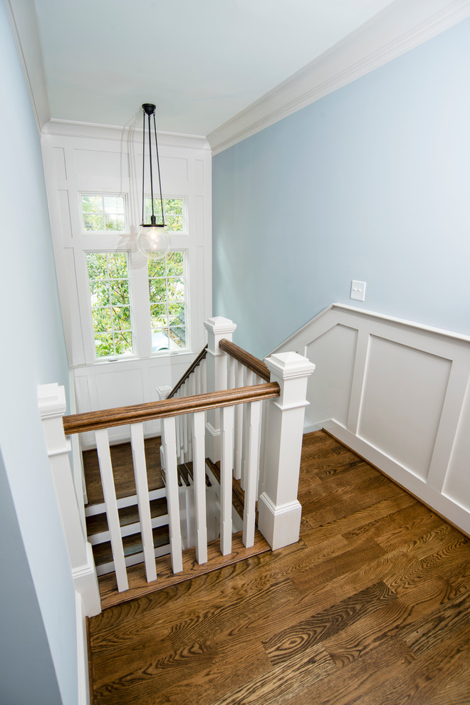 Imagen de escalera en U de estilo americano grande con escalones de madera y contrahuellas de madera pintada