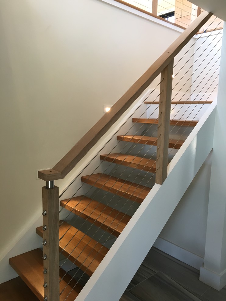 Bild på en mellanstor funkis l-trappa i målat trä, med öppna sättsteg och kabelräcke