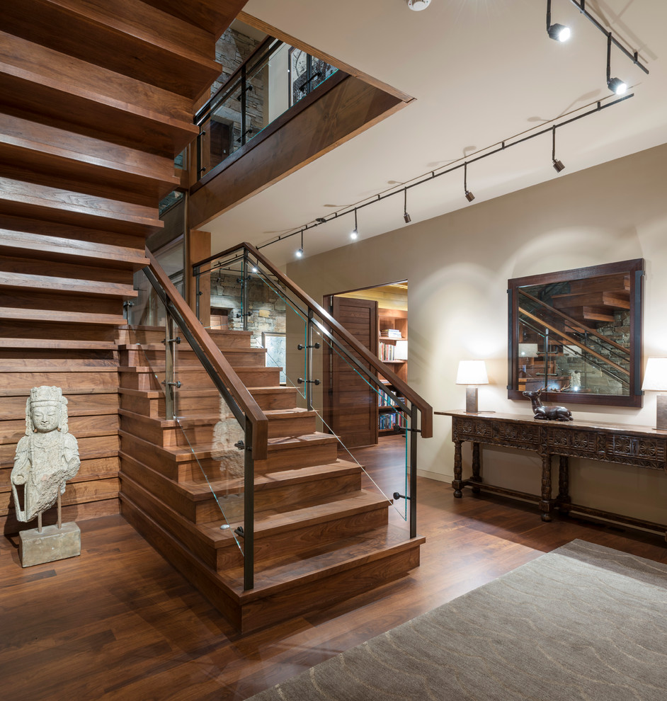 This is an example of a rustic wood u-shaped staircase in Seattle with wood risers and feature lighting.