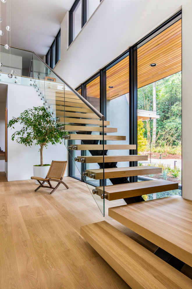Inspiration pour un grand escalier sans contremarche flottant design avec des marches en bois et un garde-corps en verre.
