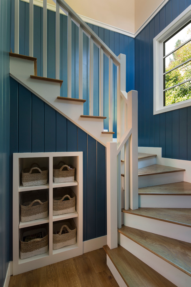 This is an example of a large coastal wood wood railing staircase in San Francisco with painted wood risers and under stair storage.