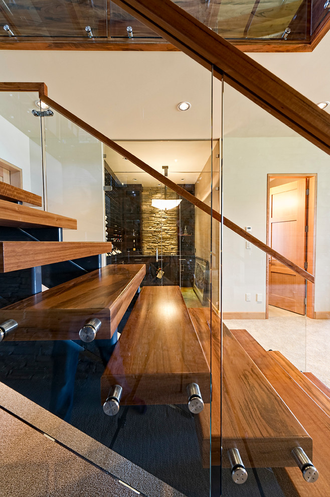 Idée de décoration pour un grand escalier sans contremarche chalet en U avec des marches en bois et un garde-corps en verre.