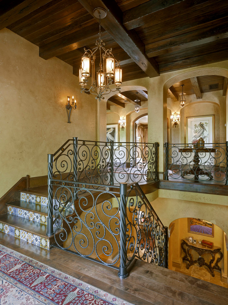 Пример оригинального дизайна: большая п-образная лестница в средиземноморском стиле с деревянными ступенями, подступенками из плитки и металлическими перилами