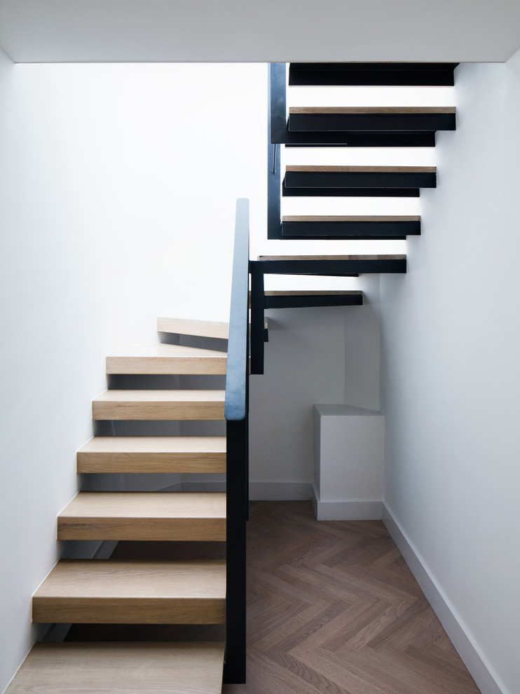 Photo of a large modern wood u-shaped staircase in London with open risers.