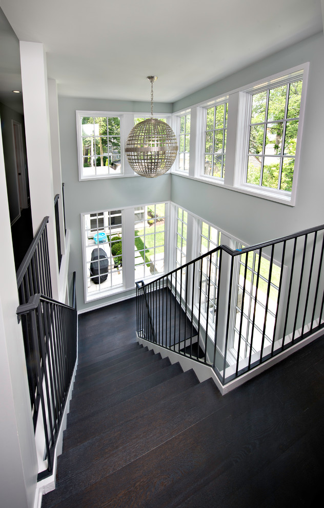 Cette photo montre un grand escalier peint moderne en U avec des marches en bois et un garde-corps en métal.