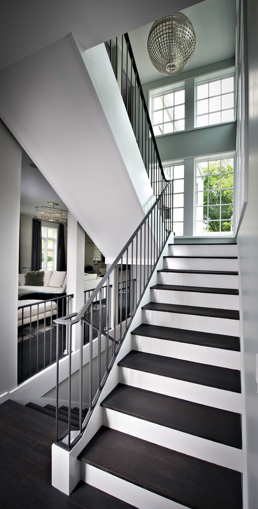Стильный дизайн: большая п-образная лестница в стиле модернизм с деревянными ступенями, крашенными деревянными подступенками и металлическими перилами - последний тренд