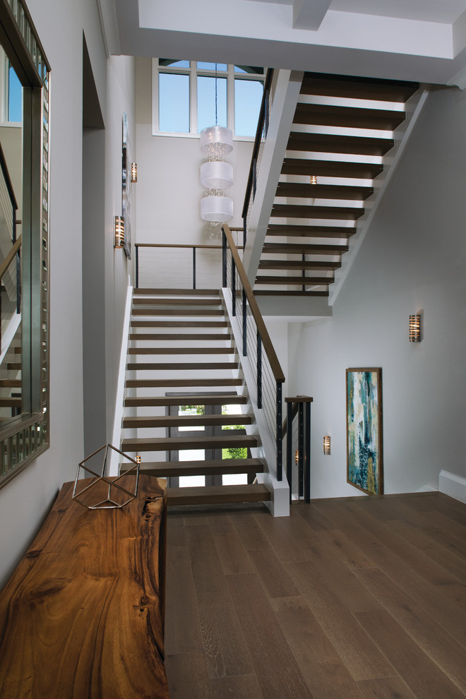 Cette image montre un grand escalier sans contremarche flottant design avec des marches en bois et un garde-corps en câble.