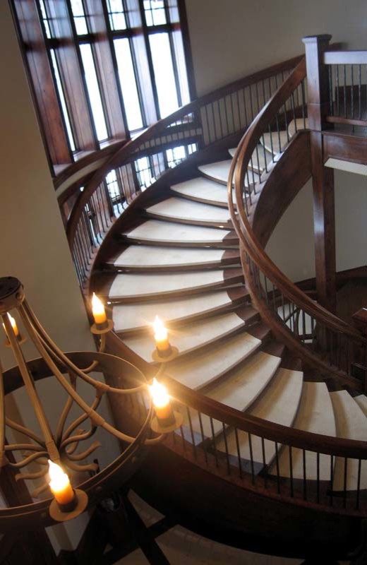 На фото: огромная изогнутая лестница в классическом стиле без подступенок с