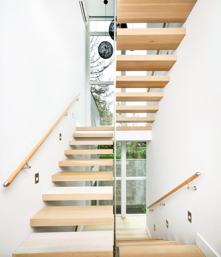 Esempio di una scala sospesa design di medie dimensioni con pedata in legno, alzata in legno e parapetto in legno
