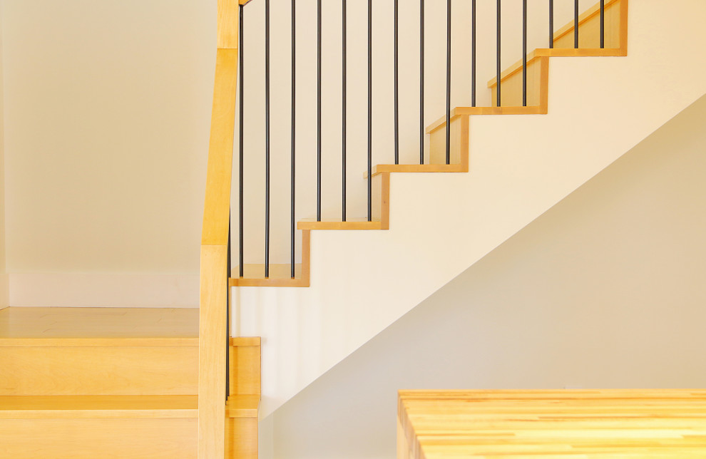 Ejemplo de escalera en L escandinava de tamaño medio con escalones de madera, contrahuellas de madera y barandilla de metal