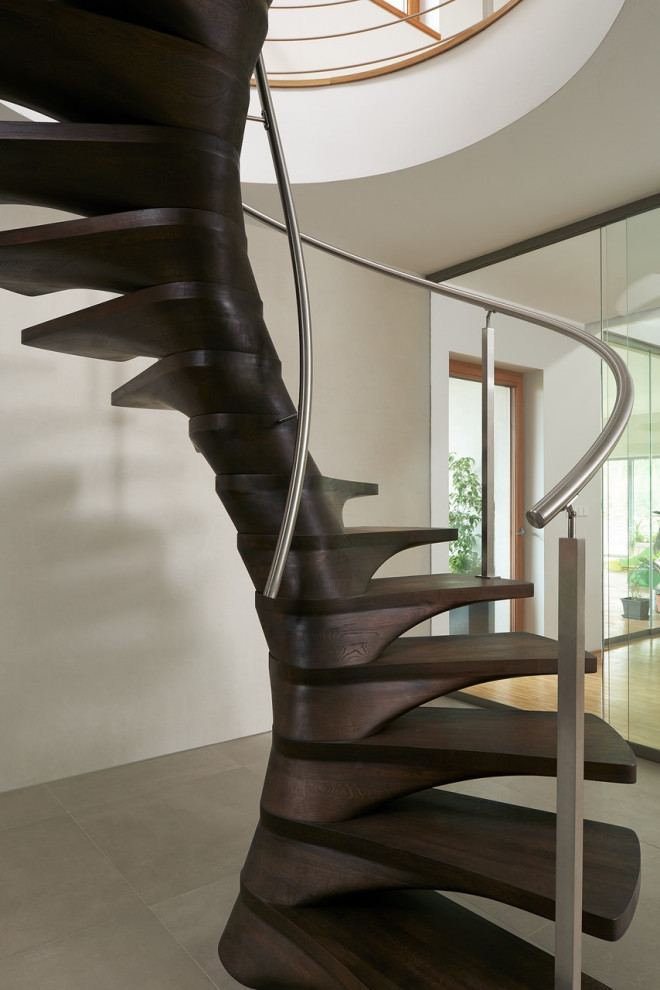 Пример оригинального дизайна: большая винтовая лестница в стиле модернизм с деревянными ступенями и металлическими перилами