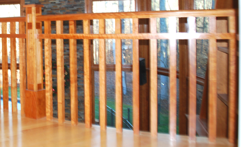 На фото: огромная изогнутая деревянная лестница в стиле кантри с деревянными ступенями