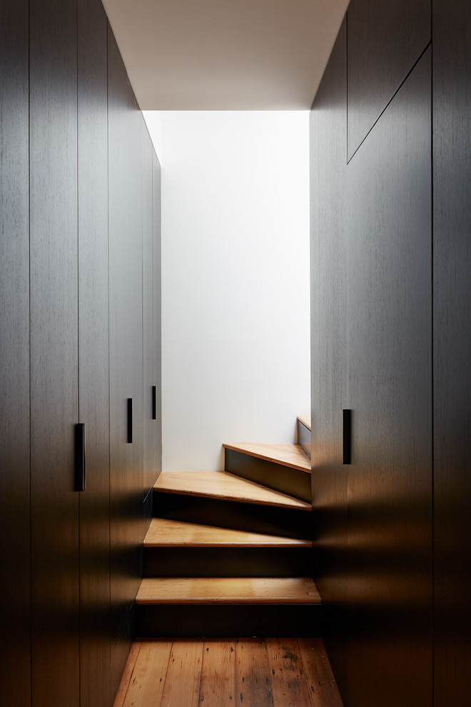 На фото: угловая металлическая лестница среднего размера в стиле модернизм с деревянными ступенями с