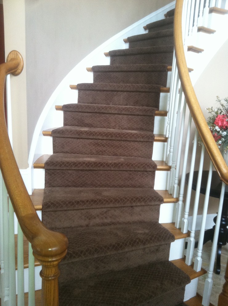Cette photo montre un grand escalier peint courbe chic avec des marches en bois.