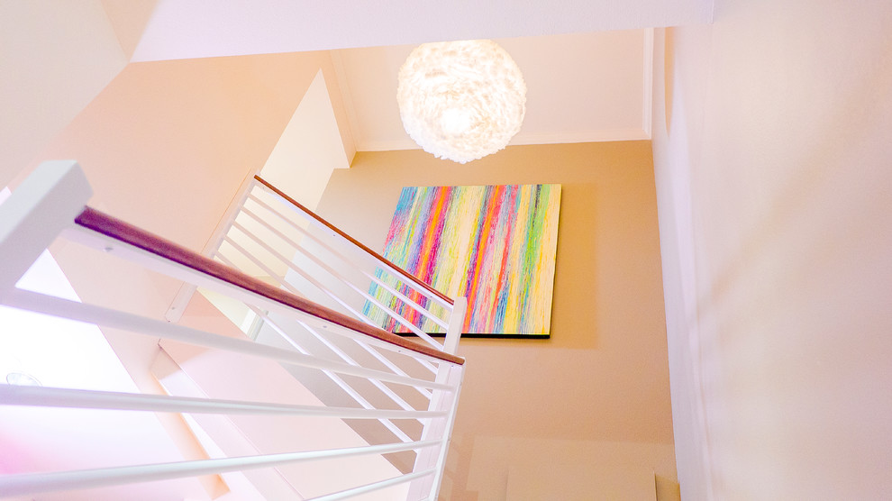 На фото: угловая лестница среднего размера в современном стиле с ступенями с ковровым покрытием, ковровыми подступенками и деревянными перилами с