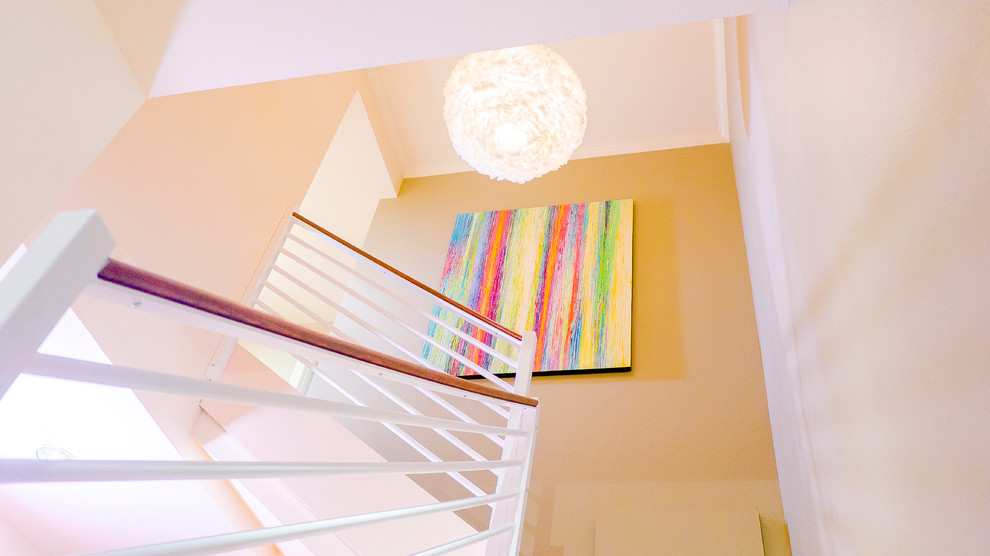 Imagen de escalera en L contemporánea de tamaño medio con escalones enmoquetados, contrahuellas enmoquetadas y barandilla de madera