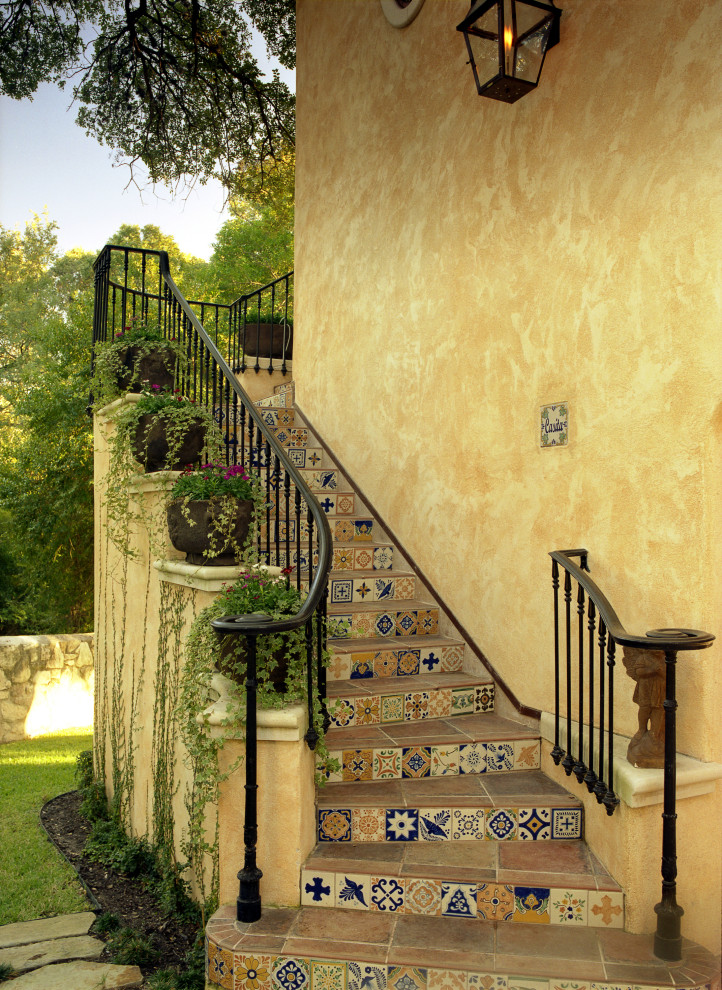 На фото: изогнутая лестница среднего размера в стиле фьюжн с ступенями из плитки, подступенками из плитки и металлическими перилами с