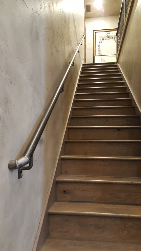 Ejemplo de escalera recta rústica con escalones de madera, contrahuellas de madera y barandilla de metal