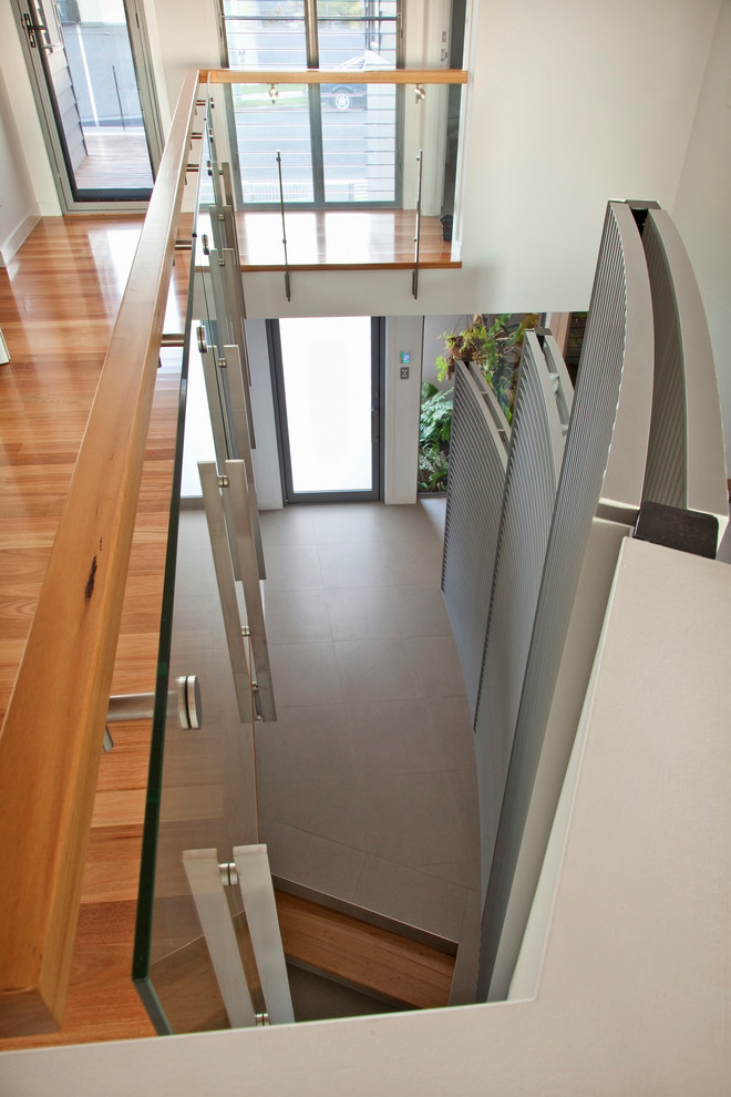 Imagen de escalera curva contemporánea grande con escalones de madera y barandilla de madera