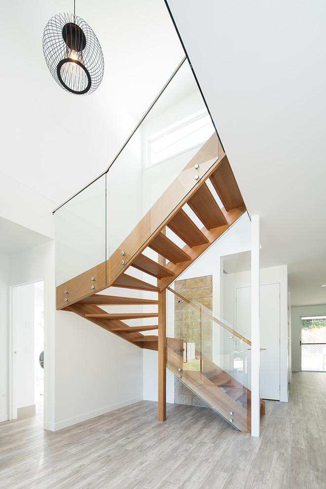Foto de escalera en U exótica pequeña con escalones de madera y barandilla de vidrio