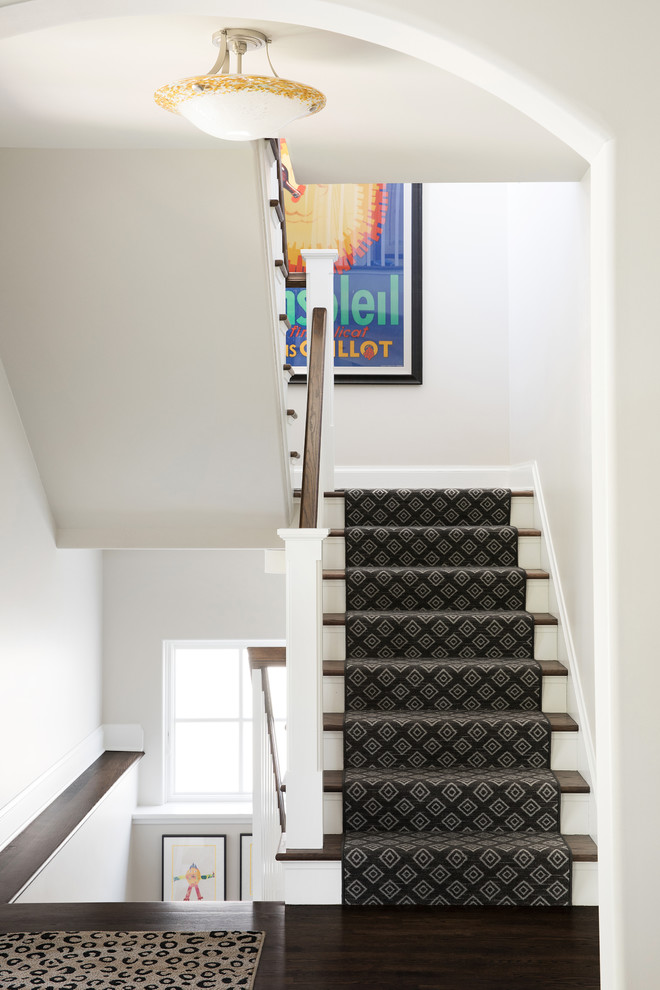 На фото: п-образная лестница в стиле неоклассика (современная классика) с ступенями с ковровым покрытием, ковровыми подступенками и деревянными перилами с