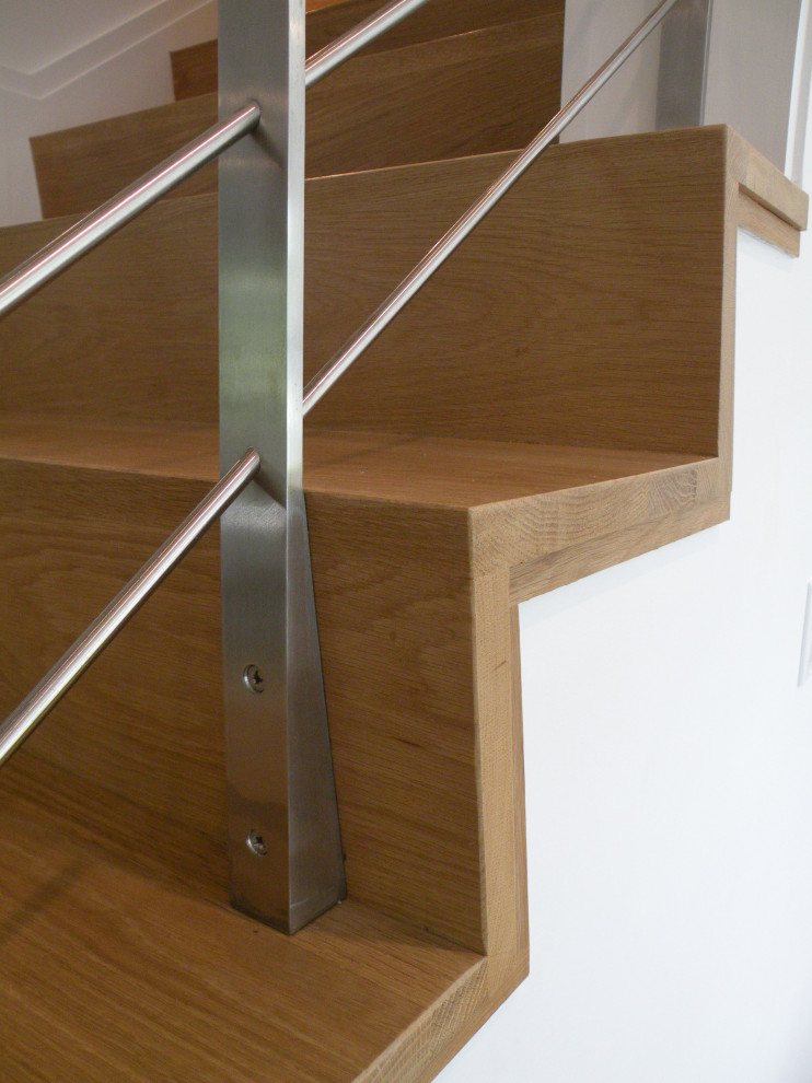 Immagine di una grande scala a rampa dritta minimalista con pedata in legno, alzata in legno e parapetto in metallo