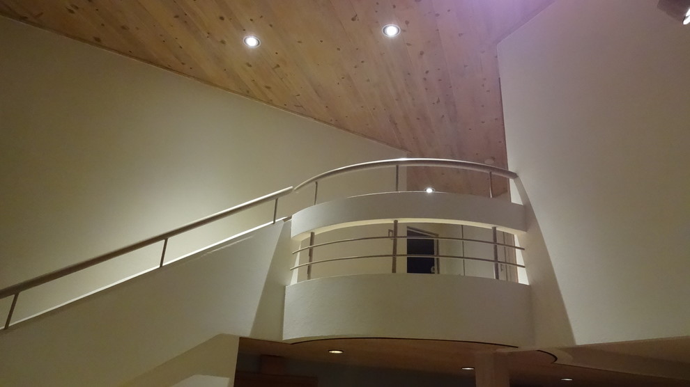 Diseño de escalera suspendida actual de tamaño medio con escalones de madera, contrahuellas de madera y barandilla de metal