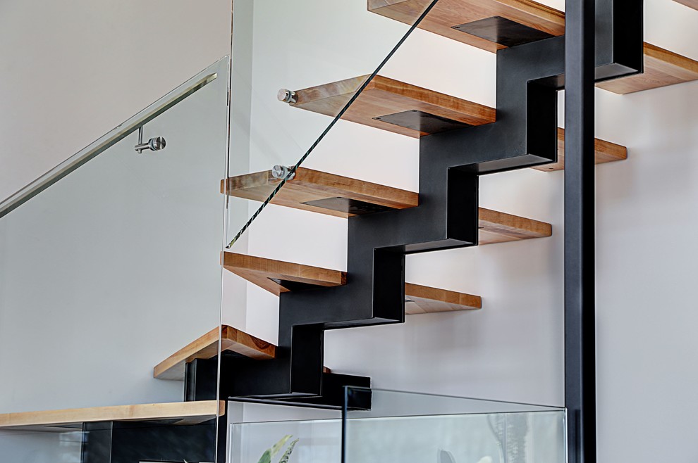 Cette image montre un escalier sans contremarche minimaliste en L avec des marches en bois et un garde-corps en verre.