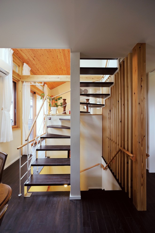 Bild på en mellanstor funkis svängd trappa i trä, med öppna sättsteg och räcke i flera material