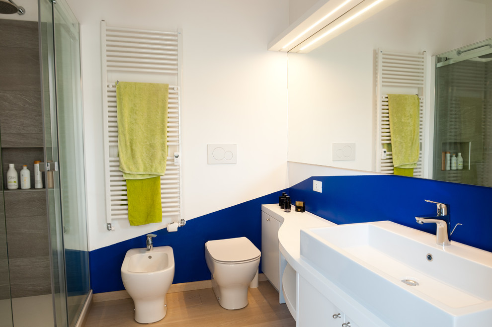Стильный дизайн: главная ванная комната среднего размера в современном стиле с плоскими фасадами, белыми фасадами, двойным душем, унитазом-моноблоком, синей плиткой, каменной плиткой, белыми стенами, светлым паркетным полом, раковиной с несколькими смесителями, столешницей из дерева, коричневым полом и душем с раздвижными дверями - последний тренд