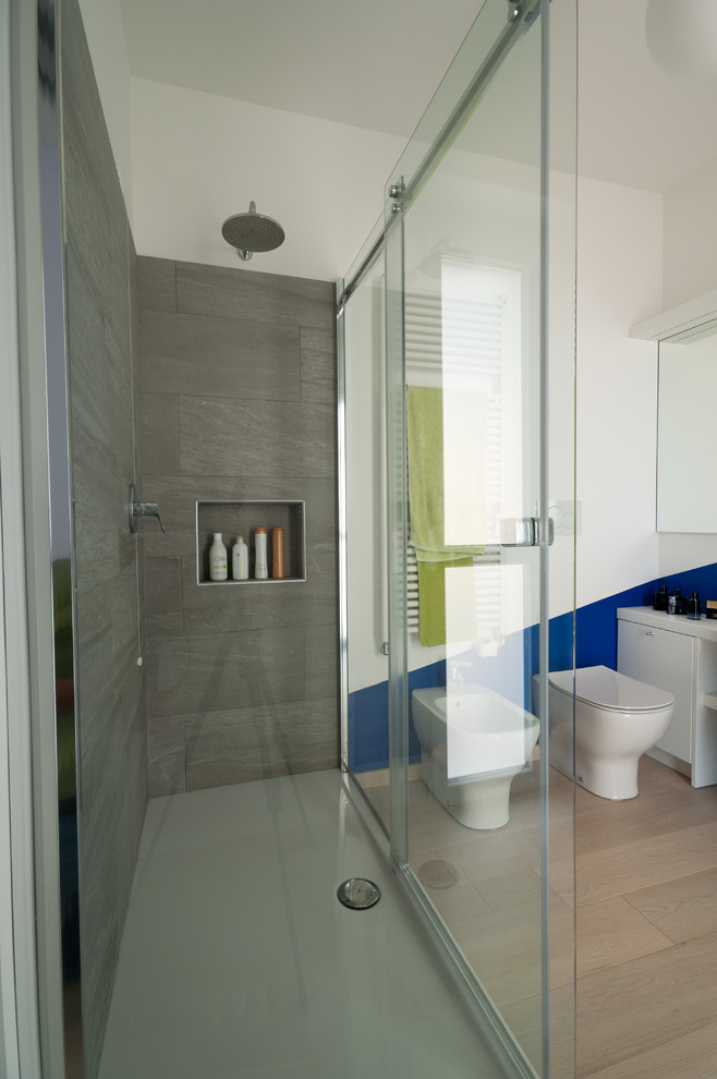 Design ideas for a medium sized contemporary ensuite bathroom in Other with flat-panel cabinets, white cabinets, a double shower, a two-piece toilet, blue tiles, stone tiles, white walls, light hardwood flooring, a trough sink, wooden worktops, a sliding door and brown floors.