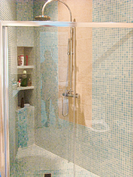Foto di una stanza da bagno con doccia minimalista di medie dimensioni con ante lisce, ante in legno chiaro, doccia a filo pavimento, WC sospeso, piastrelle blu, piastrelle a mosaico, pareti bianche, pavimento in gres porcellanato, lavabo da incasso e top piastrellato