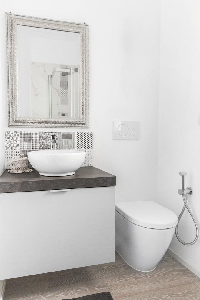 Foto de cuarto de baño actual con armarios con paneles lisos, puertas de armario blancas, baldosas y/o azulejos negros, paredes blancas, lavabo sobreencimera, suelo gris y encimeras grises