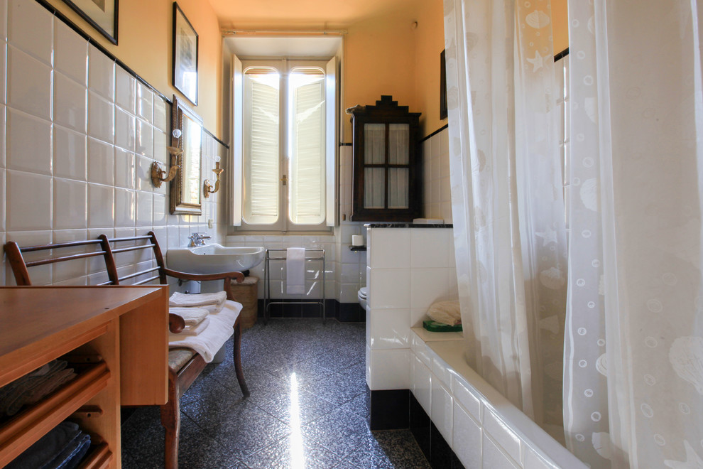 Inspiration pour une salle de bain traditionnelle avec une baignoire posée, un carrelage blanc, des carreaux de céramique, un mur jaune, un sol en carrelage de porcelaine, un lavabo de ferme et un sol noir.