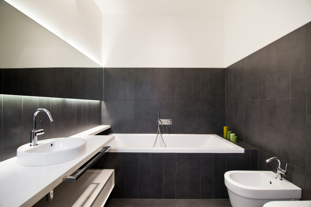 Cette photo montre une grande salle de bain principale moderne avec une baignoire posée, des dalles de pierre, un mur blanc et une vasque.