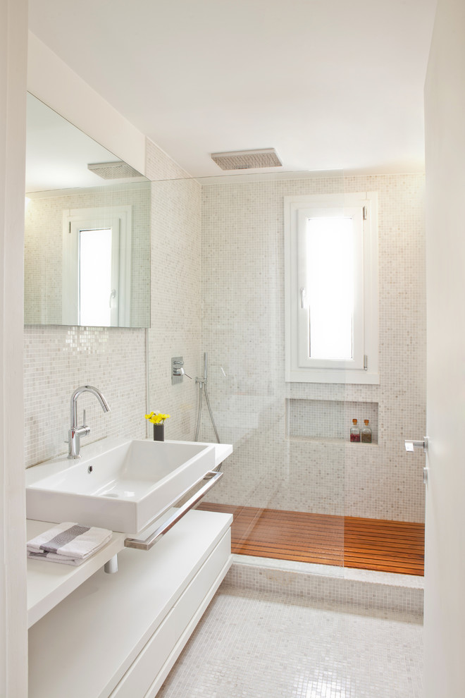 Foto på ett funkis badrum med dusch, med släta luckor, vita skåp, en dusch i en alkov, vit kakel, mosaik, vita väggar, mosaikgolv och ett avlångt handfat
