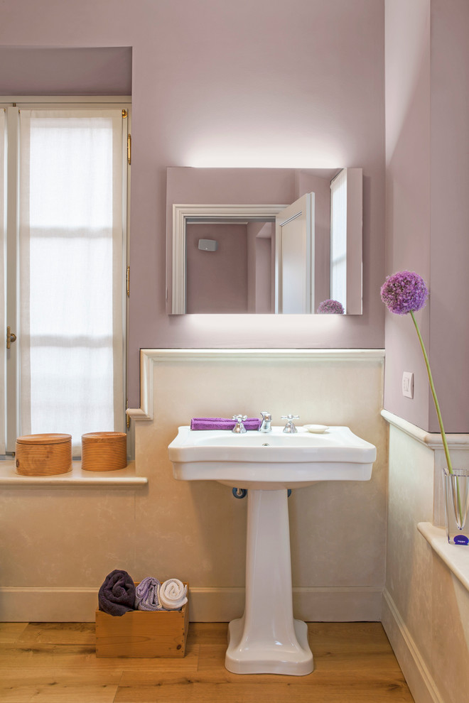 Foto på ett vintage badrum, med lila väggar, ett piedestal handfat och mellanmörkt trägolv