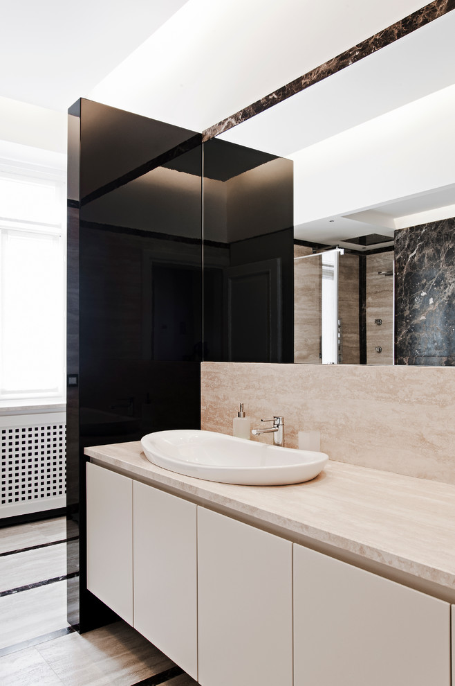 Cette photo montre une salle de bain tendance avec des portes de placard blanches, des dalles de pierre et une vasque.