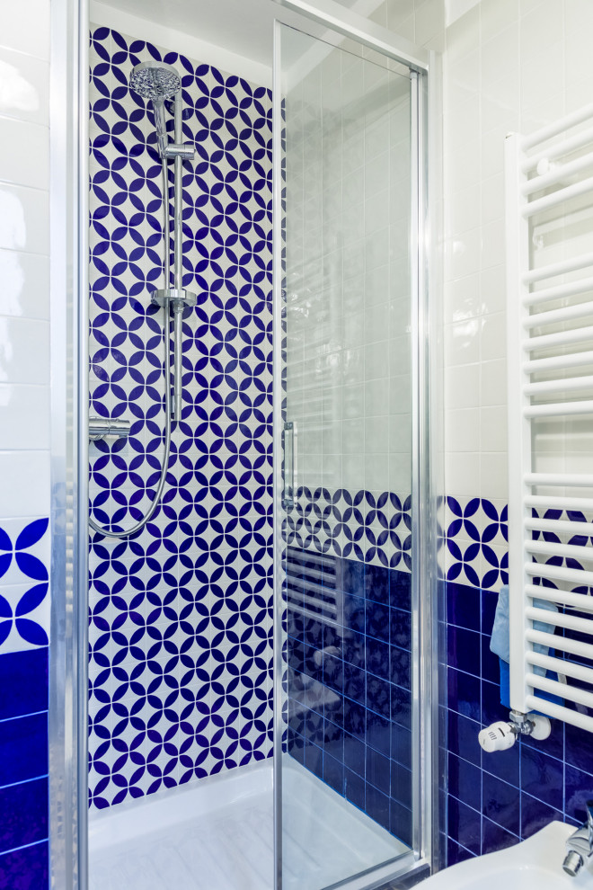 Idéer för att renovera ett litet funkis blå blått badrum med dusch, med luckor med upphöjd panel, vita skåp, en dusch i en alkov, flerfärgad kakel, porslinskakel, vita väggar, klinkergolv i porslin, ett fristående handfat, kaklad bänkskiva, flerfärgat golv och dusch med gångjärnsdörr