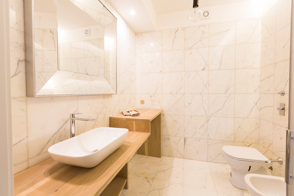 Modern inredning av ett stort beige beige badrum med dusch, med öppna hyllor, beige skåp, en hörndusch, vit kakel, marmorkakel, vita väggar, marmorgolv, träbänkskiva, vitt golv, en toalettstol med hel cisternkåpa, ett fristående handfat och dusch med gångjärnsdörr
