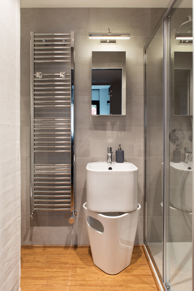 Foto di una stanza da bagno contemporanea di medie dimensioni con ante lisce, ante bianche, piastrelle grigie, piastrelle in ceramica, parquet chiaro e lavabo sospeso