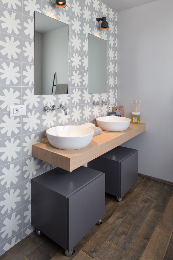 ミラノにあるコンテンポラリースタイルのおしゃれな浴室 (フラットパネル扉のキャビネット、グレーのキャビネット、白いタイル、グレーのタイル、セラミックタイル、グレーの壁、濃色無垢フローリング、ベッセル式洗面器、木製洗面台、ベージュのカウンター) の写真